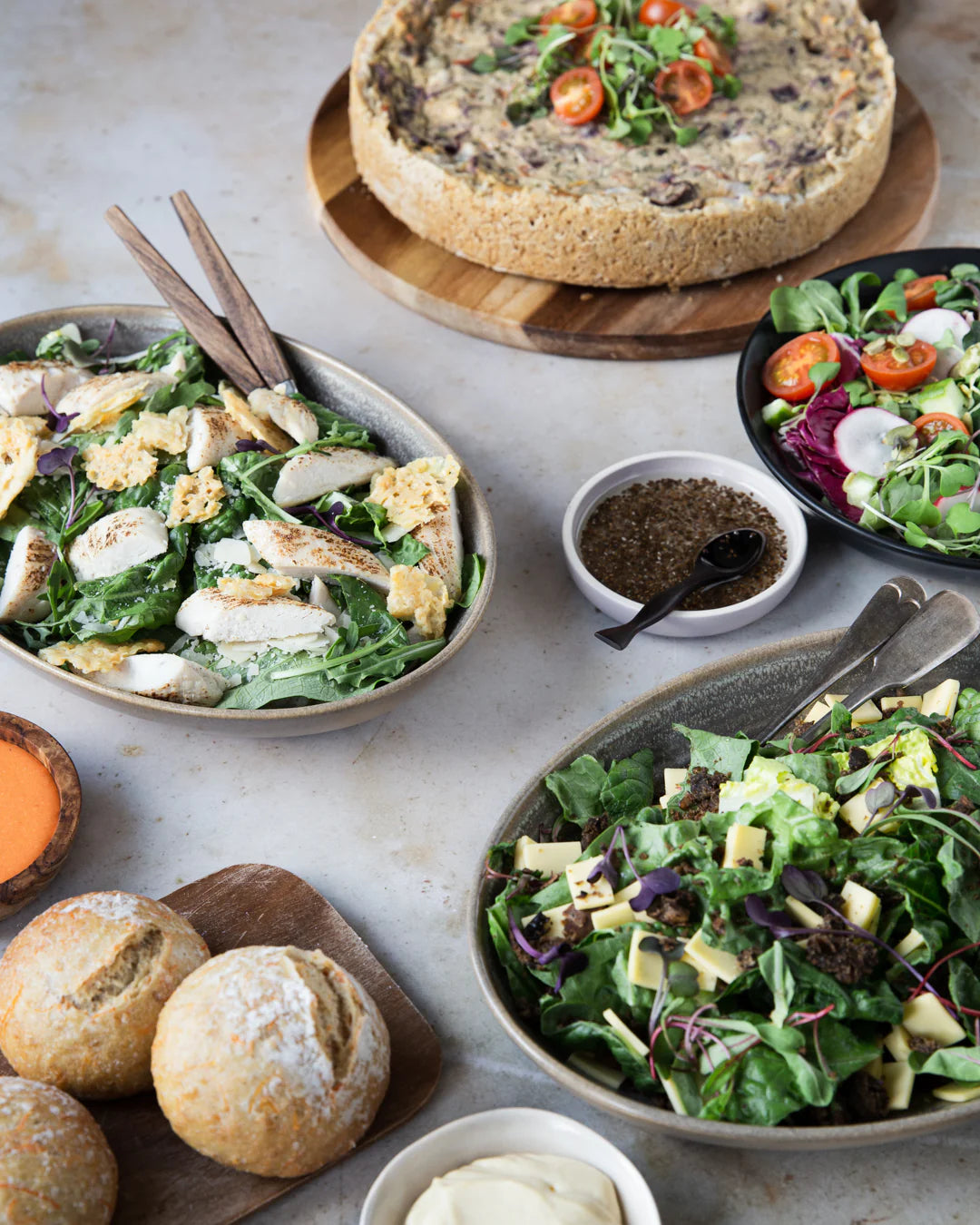 Ruokaisa kattaus piirakalla, kauden salaateilla ja itse leivotulla leivällä.