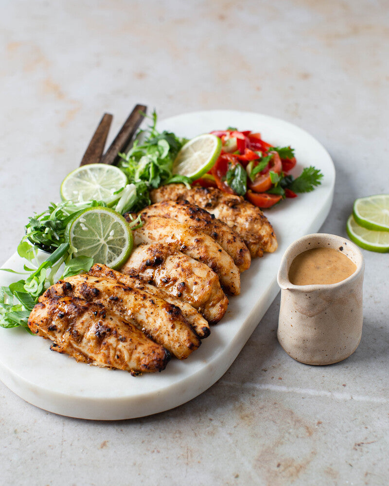 Satay-broileria ja tuoretomaattisalsaa marmorisella tarjoiluastialla.