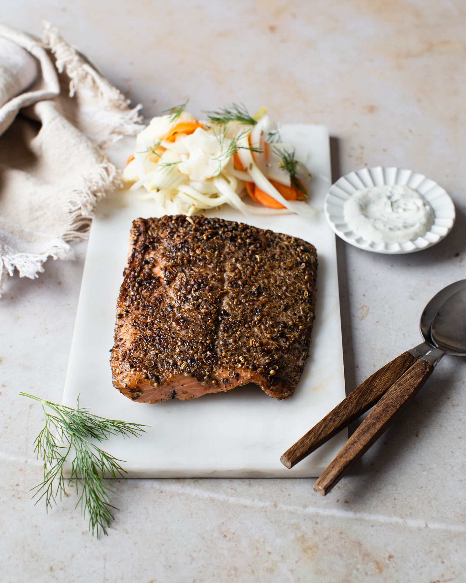 Lohipastramia ja pikkelöityjä kasviksia tarjoiluastialla.