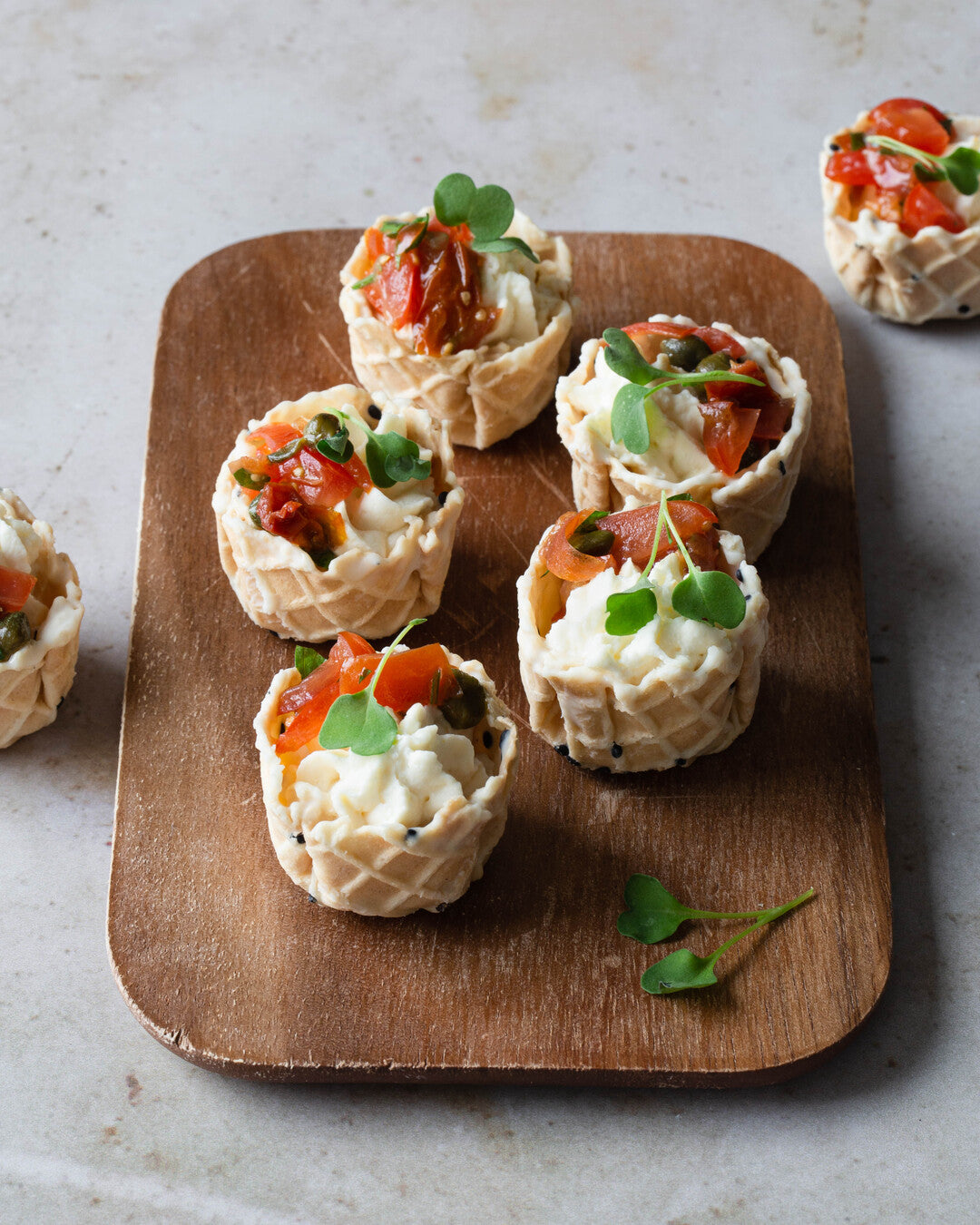 Vaahdotettua fetaa ja marinoitua tomaattia vohvelikorissa - cocktailpalat tarjoiluastialla.