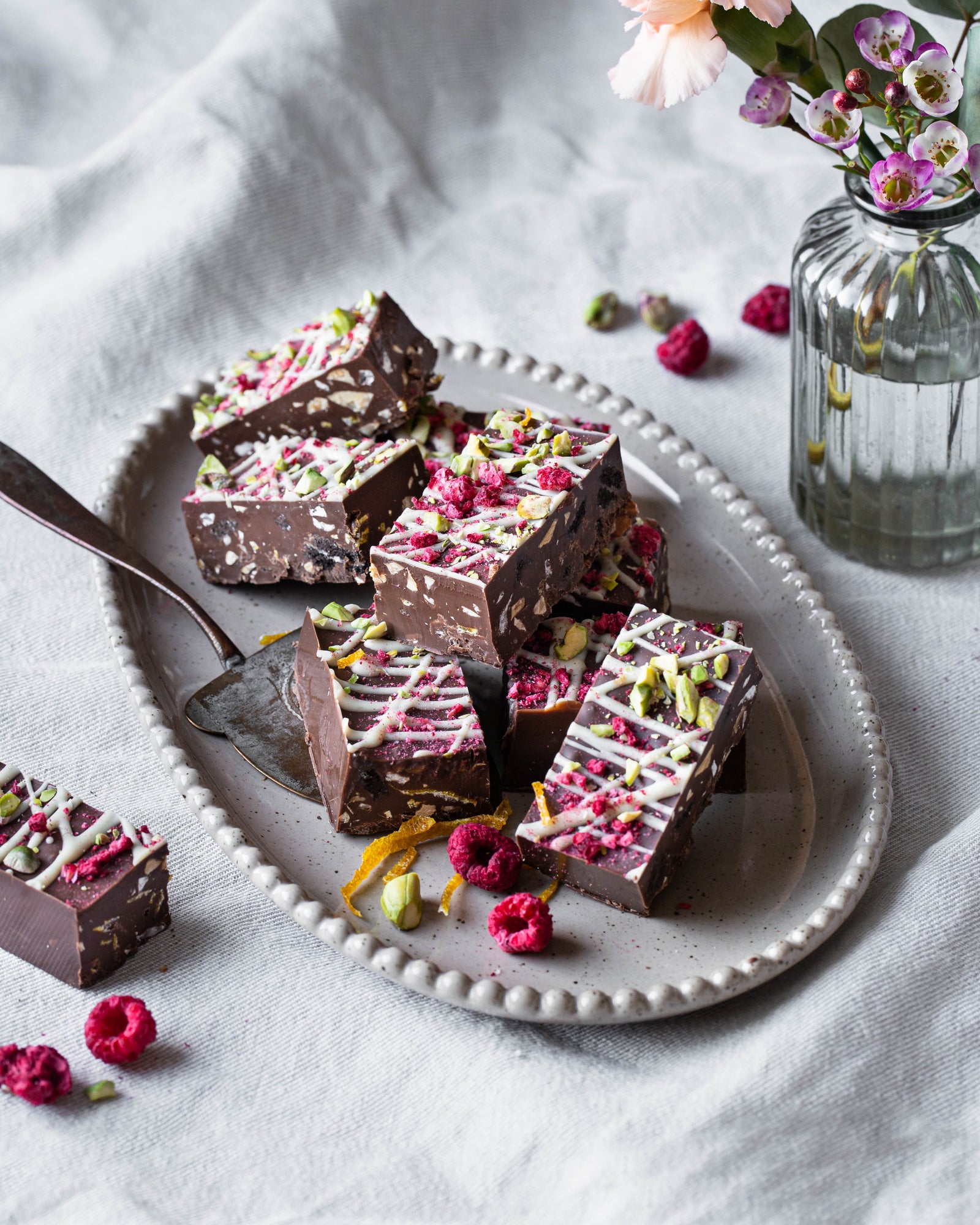 Täyteläistä vegaanista rocky road -leivosta kuutioina tarjoiluastialla.