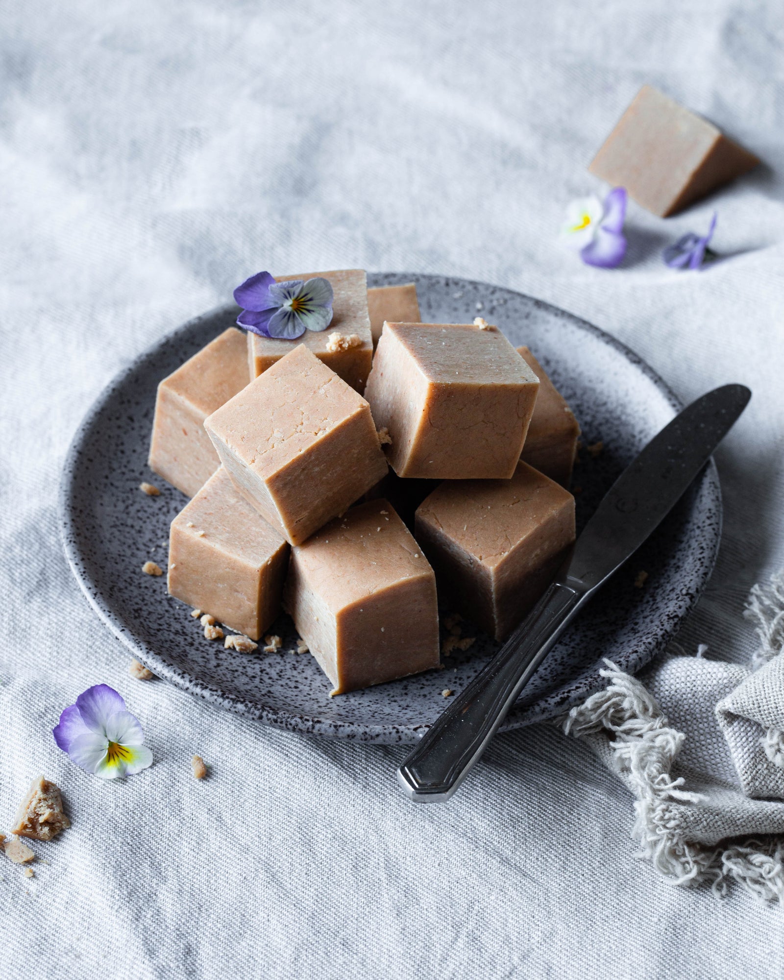 Kuutioiksi leikattuja kookos-maapähkinäfudge -paloja. tarjoiluastialla