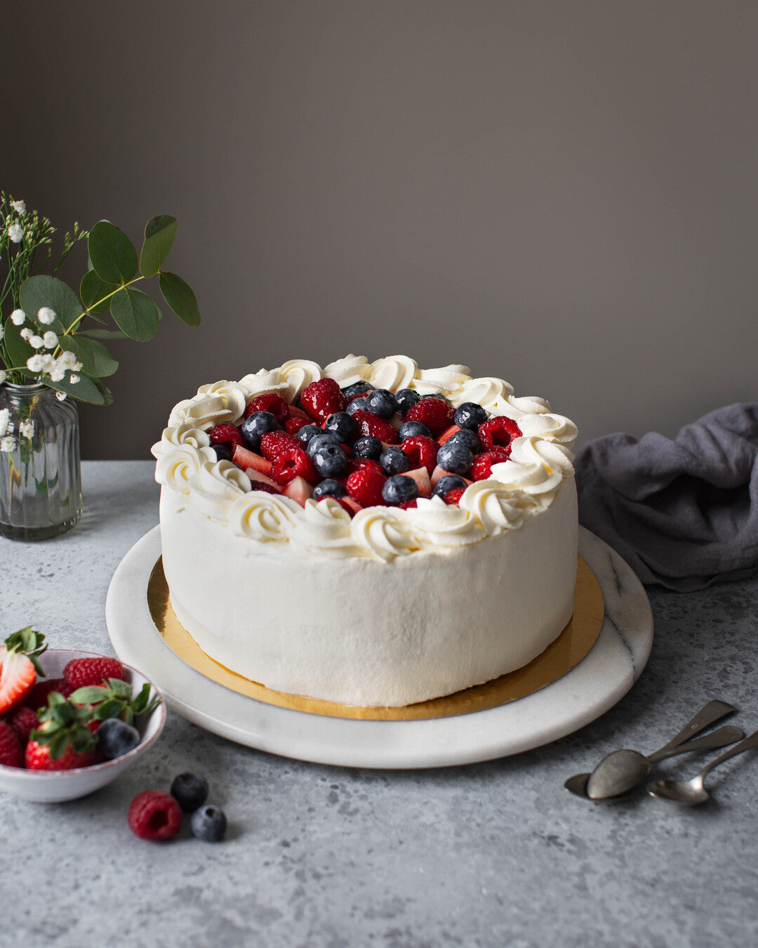 Perinteikäs marjainen kermakakku tarjoiluastialla.