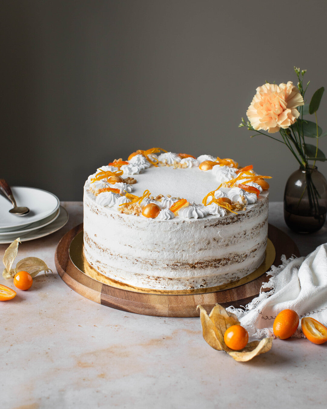 Rustiikkinen, täyteläinen porkkanatäytekakku, jonka pinnalla kumkvattia ja appelsiininkuorta.