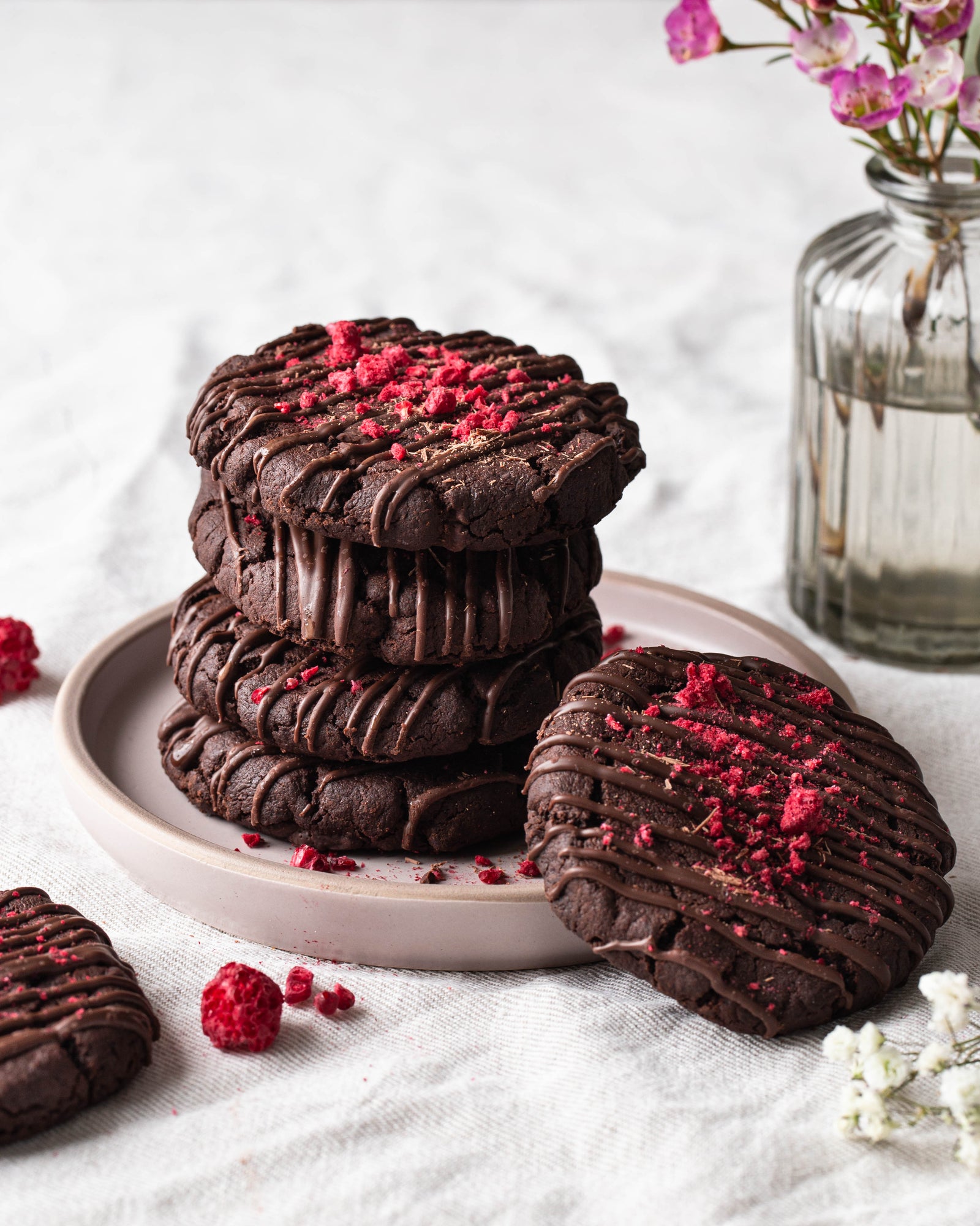 Runsaita vadelmarouheella koristeltuja suklaacookie-keksejä lautasella.