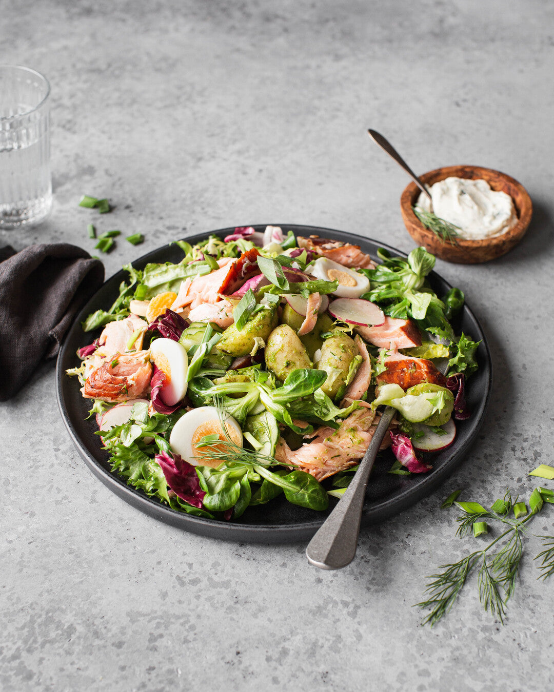 Lämminsavulohisalaattia ja piparjuurikastiketta tarjoiluastialla.